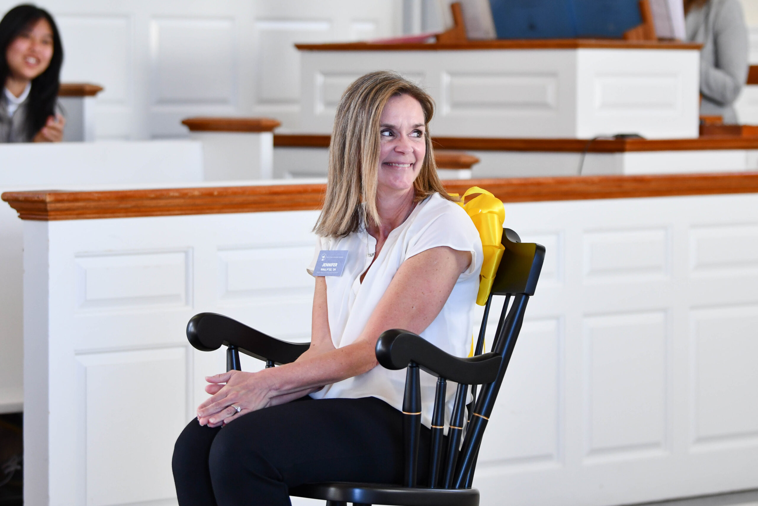 A woman smiles over her shoulder as she sits in a chair that represents the prize she has won for her work in the math department